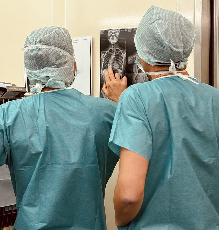 Deux chirurgiens de l'IMeD analysent une radiographie de la colonne vertébrale entière