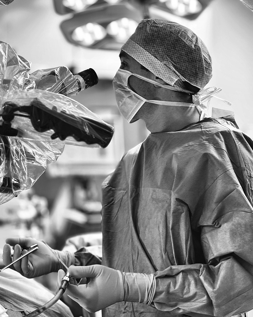 Le chirurgien guide l'instrument sous microscope, pendant une chirurgie mini-invasive